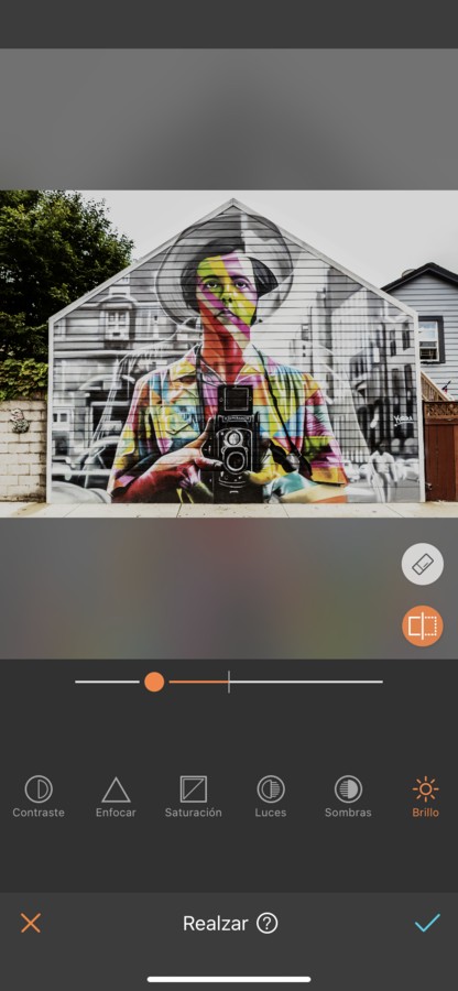 Arte urbano de un hombre sosteniendo una cámara, pintado en la fachada de una casa.