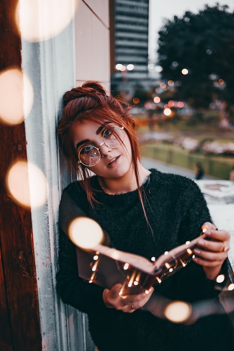 A woman with red hair with a book open being edited by Airbrush